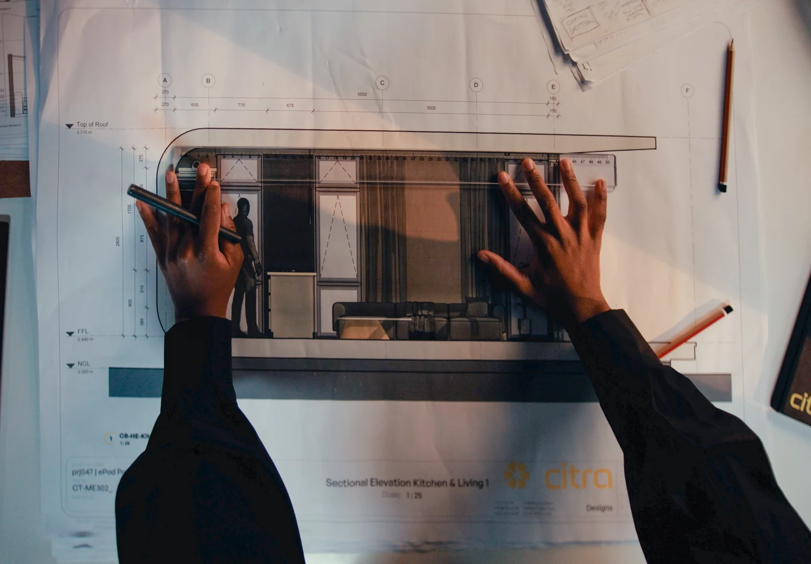 Hands working with a ruler on architectural plans for a Citra home.